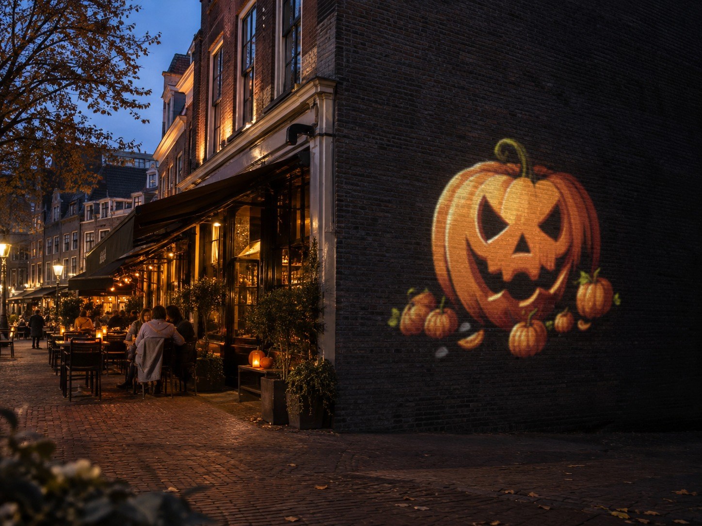 Halloween gobo projectie: pompoen geprojecteerd op de bakstenen zijgevel van een restaurant met terras